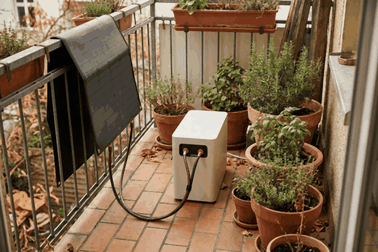 Balkonkraftwerk mit Speicher: Solarmodule am Balkongeländer, daneben eine Batterie auf dem Balkonboden.